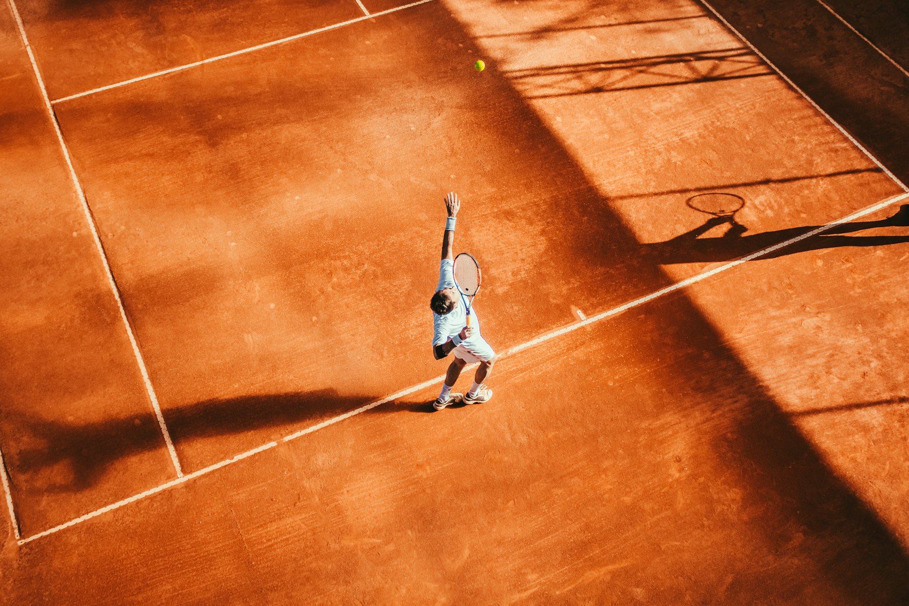 Joueur au service sur un court en terre battue